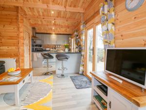 a living room and kitchen of a cabin with a flat screen tv at Little Orchard Lodge in Truro