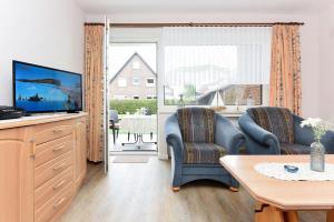 ein Wohnzimmer mit 2 Stühlen und einem TV in der Unterkunft Ferienwohnungen im Haus am Wattenmeer in Neuharlingersiel