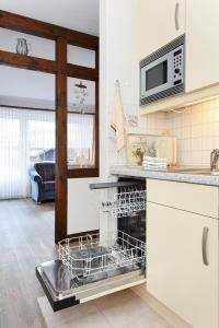 eine Küche mit einem Geschirrspüler und einer Mikrowelle in der Unterkunft Ferienwohnungen im Haus am Wattenmeer in Neuharlingersiel