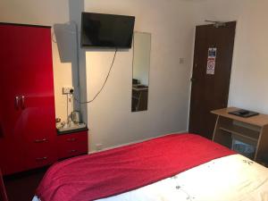a bedroom with a bed with a red dresser and a tv at Great Western Hotel Guest House in Paignton