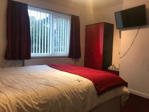 a bedroom with a bed with a red blanket and a window at Great Western Hotel Guest House in Paignton