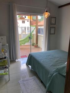 a bedroom with a bed and a door to a yard at SUITE RUA PESCADA AMARELA in Bombinhas