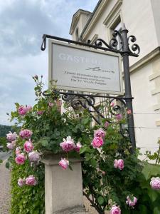 ein Schild vor einem Gebäude mit rosa Rosen in der Unterkunft Gästehaus Schönitz in Meißen