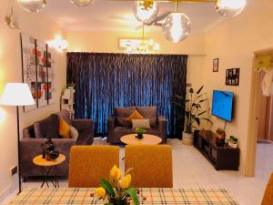 sala de estar con sofá, sillas y TV en 101 Sky Mirror Homestay en Kuala Selangor