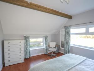 a bedroom with a bed and a window and a chair at Oscar's Pad in Llanfairpwllgwyngyll
