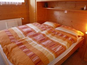 - un lit avec des couvertures orange et blanches dans l'établissement Chalet Lò Batcho by Interhome, à Zinal