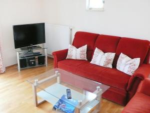 un soggiorno con divano rosso e TV di Apartment Bibelöd-7 by Interhome a Ruhpolding