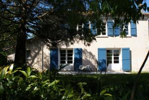 una casa con persianas azules y un árbol en Château De Grenier Gite, en Saint-Léger