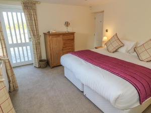 a bedroom with a large bed and a window at Fogga Croft Cottage in Skipton