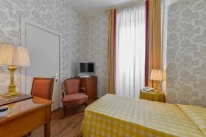 a hotel room with a bed and a desk and a television at Albergo Alla Posta in Trieste