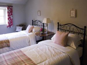 a bedroom with two beds and a table with a window at Town Head Farm in Malham