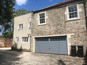 a large brick building with two garage doors at The Hole in the Wall, Midsomer Norton, Nr Bath & Longleat in Bath