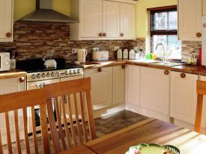 a kitchen with white cabinets and a stove top oven at Holiday Home Glenn Cottage by Interhome in Uig
