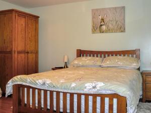 a bedroom with a bed with a wooden head board at Holiday Home Glenn Cottage by Interhome in Uig