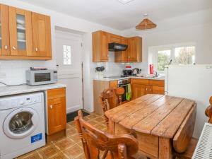 een keuken met een houten tafel en een witte koelkast bij Bowden Head Farmhouse Cottage in Highpeak Junction