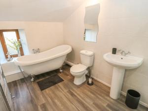 a bathroom with a tub and a toilet and a sink at Boshaw Cottage in Holmfirth +13 photos