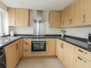 a kitchen with wooden cabinets and a large appliance at Bedlinog in Amlwch