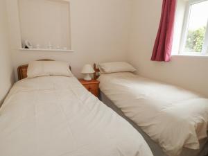 two beds in a small room with a window at Bedlinog in Amlwch