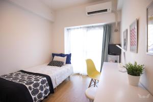 Schlafzimmer mit einem Bett, einem Tisch und einem Fenster in der Unterkunft Escort Haruyoshi in Fukuoka