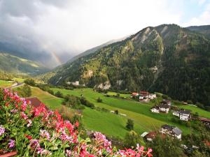 einen Regenbogen über einem grünen Tal mit Häusern und Blumen in der Unterkunft Apartment Berneckblick by Interhome in Kauns