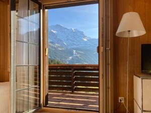 ヴェンゲンにあるApartment Jungfrau an der Ledi-1 by Interhomeの山の景色を望むガラスのスライドドア付きの客室です。