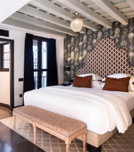 a bedroom with a large white bed and a bench at Boutique Hotel Casa Cánovas in Cádiz