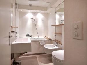 a white bathroom with a sink and a toilet at Apartment Chesa Villasimius by Interhome in Celerina