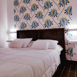 una camera da letto con un letto bianco e carta da parati floreale di Gio House Pompei a Pompei