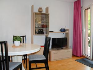a dining room with a table and a tv at Apartment App- 17 by Interhome in Caslano