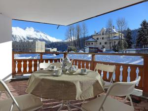 Apartment Chesa Fuolla Verda A8 by Interhome في سيليرينا: طاولة وكراسي على شرفة مع جبال مغطاة بالثلج
