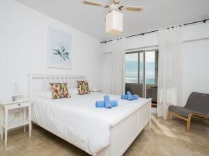a white bedroom with a bed and a chair at Apartment Marina Bay-2 by Interhome in Estepona
