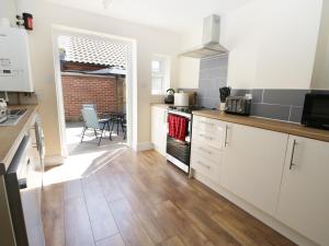 cocina con armarios blancos y encimera en White Rose Cottage, en Guisborough