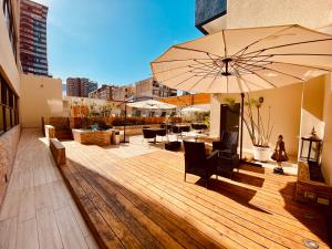 una terrazza in legno con ombrellone, sedie e tavoli di Gran Cavancha Suite a Iquique