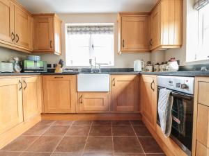 a kitchen with wooden cabinets and a sink at Orchard Cottage in Tenbury