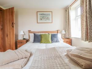 a bedroom with a large bed and two windows at Orchard Cottage in Tenbury