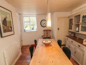een keuken met een houten tafel met stoelen en een klok bij Clevelyn in Staithes