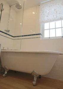 eine weiße Badewanne in einem Badezimmer mit Fenster in der Unterkunft Riverside cottage walking distance into Caernarfon in Caernarfon