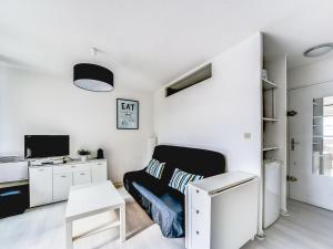 ein weißes Schlafzimmer mit einem schwarzen Sofa und einem Schreibtisch in der Unterkunft Apartment Les Floralies II-7 by Interhome in Le Grau-du-Roi