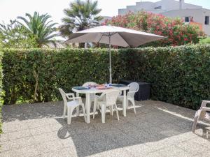 a table and chairs with an umbrella on a patio at Apartment Les Frégates by Interhome in Saint-Cyprien-Plage