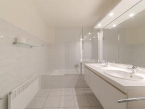 a white bathroom with a sink and a tub at Apartment Strandhuis with balcony by Interhome in Bredene