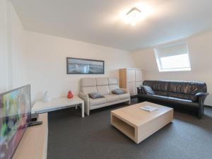 a living room with a couch and a tv at Apartment Strandhuis with balcony by Interhome in Bredene