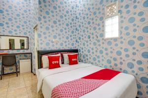 ein Schlafzimmer mit einem Bett mit roten Kissen darauf in der Unterkunft OYO 90642 Lancar Homestay Syariah in Tlekung
