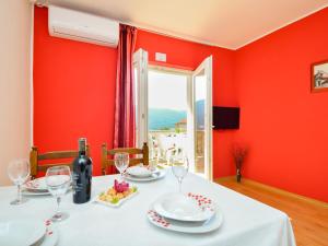 a dining room with red walls and a table with wine glasses at Apartment Miro-1 by Interhome in Grebaštica