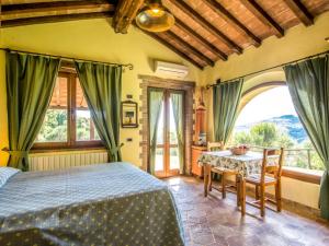1 dormitorio con cama, mesa y ventanas en Holiday Home Casale Belvedere by Interhome en Roccastrada