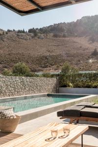 a swimming pool with a table and a bench at Casa Cook Rhodes (Adults Only) in Kolimbia