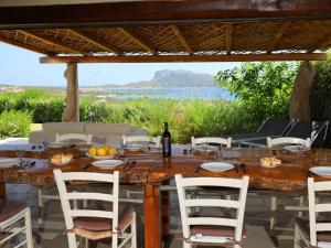 een grote houten tafel met stoelen en een fles wijn bij Holiday Home Iris by Interhome in Marinella