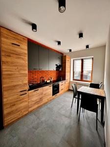 una cocina con armarios de madera y una mesa con sillas. en Apartament na Maja -2-, en Skierniewice