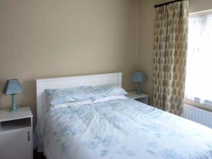 a bedroom with a bed and two lamps and a window at Ocean View in Ballinskelligs