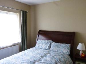 a bedroom with a bed with a blue comforter and a window at Ocean View in Ballinskelligs