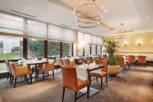 a restaurant with tables and chairs and a chandelier at H+ Hotel Bochum in Bochum
